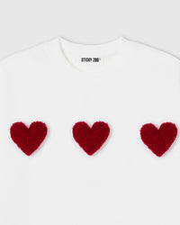 Close-up of plush heart appliques showing textured sherpa surface and dimensional depth on white cotton
