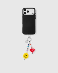 Phone with smiley heart charm strap attached on light background