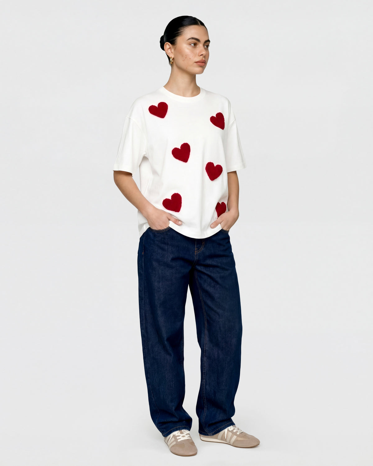 {{Model is wearing size M}} Close-up of hand-stitched deep red plush heart on white cotton showing textured surface and dimensional depth