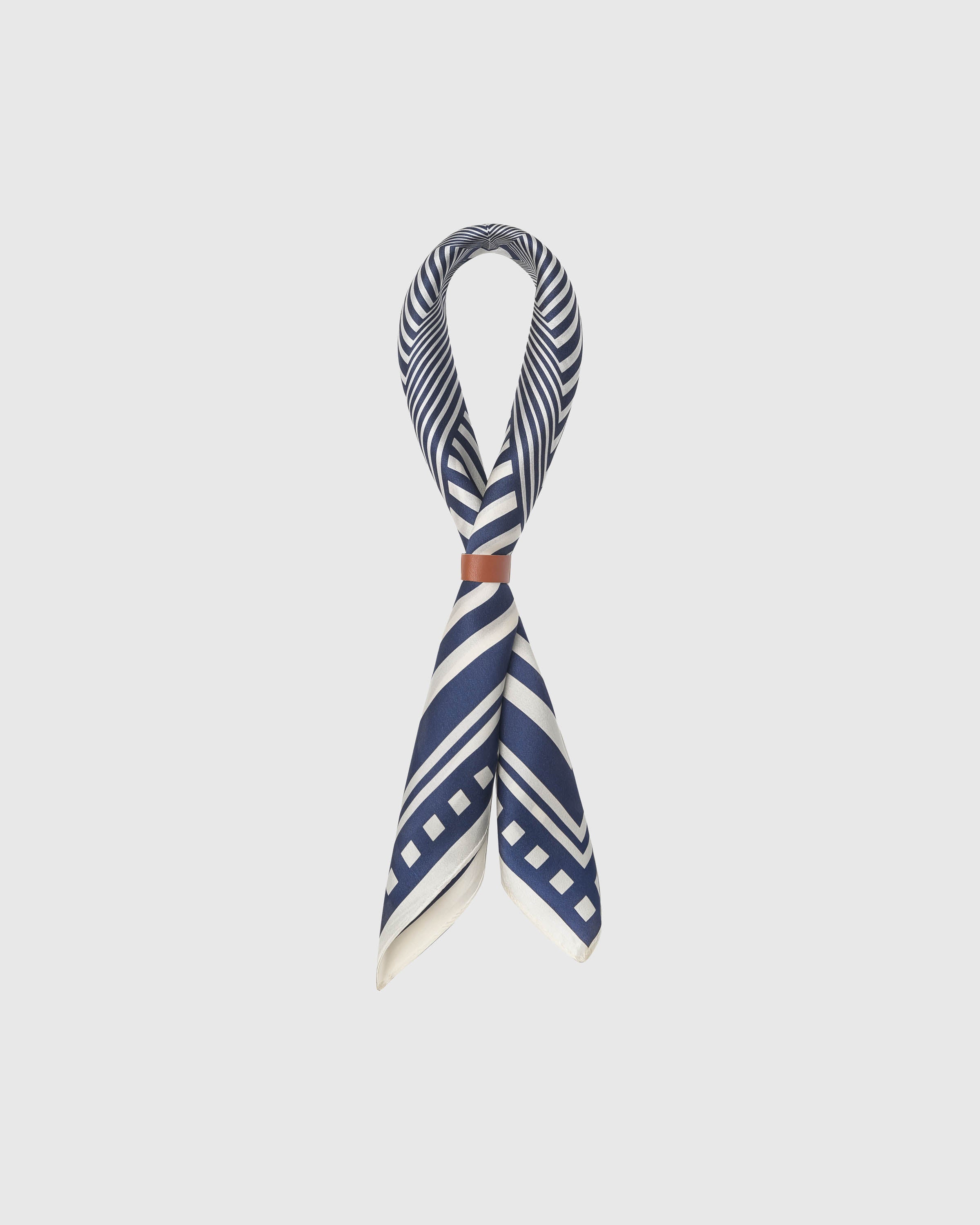 STICKYZOO optical stripe silk scarf threaded through a leather ring showing the chevron pattern wrapping the fold