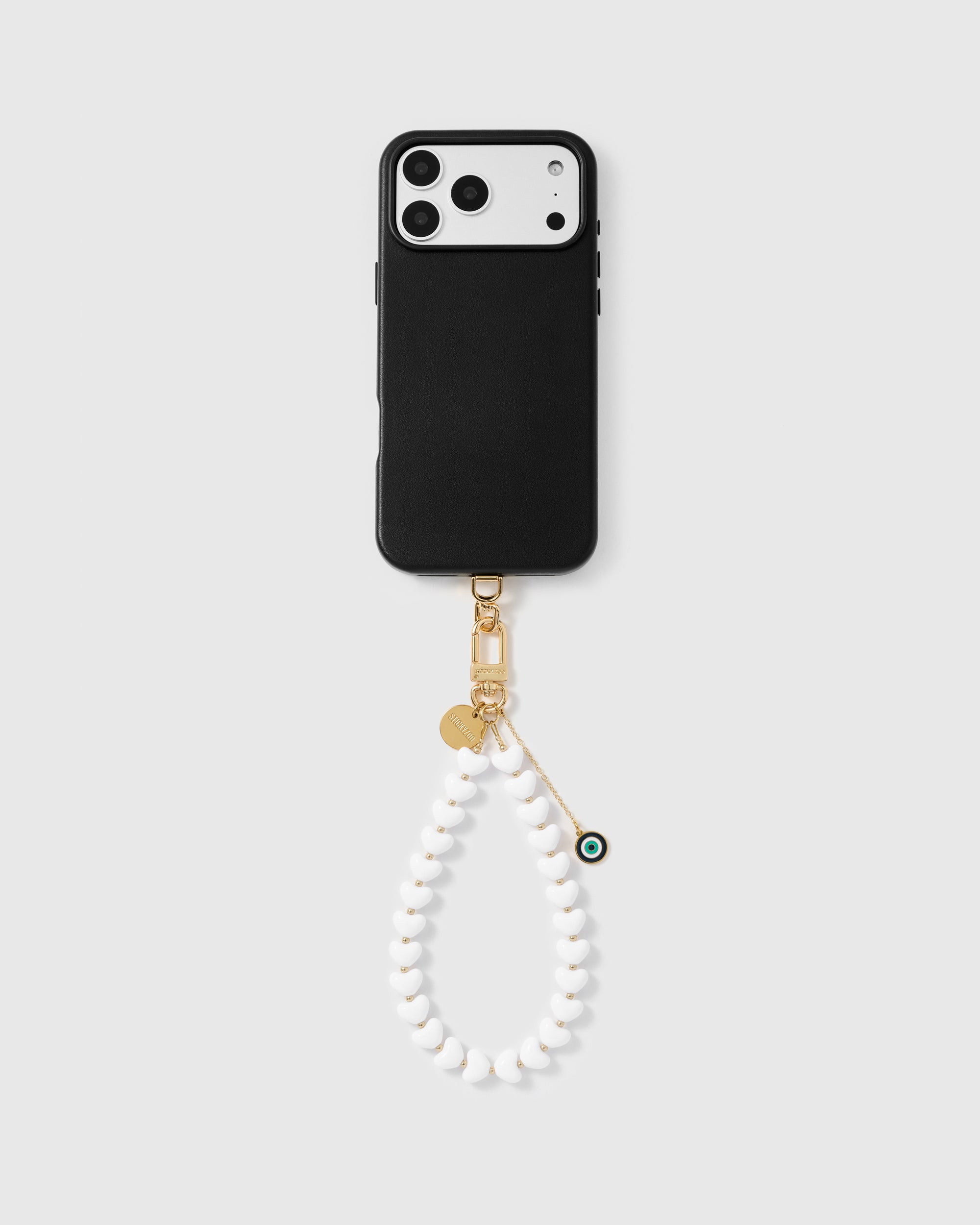 White heart phone strap with eye amulet worn as a wrist loop showing hands-free carry