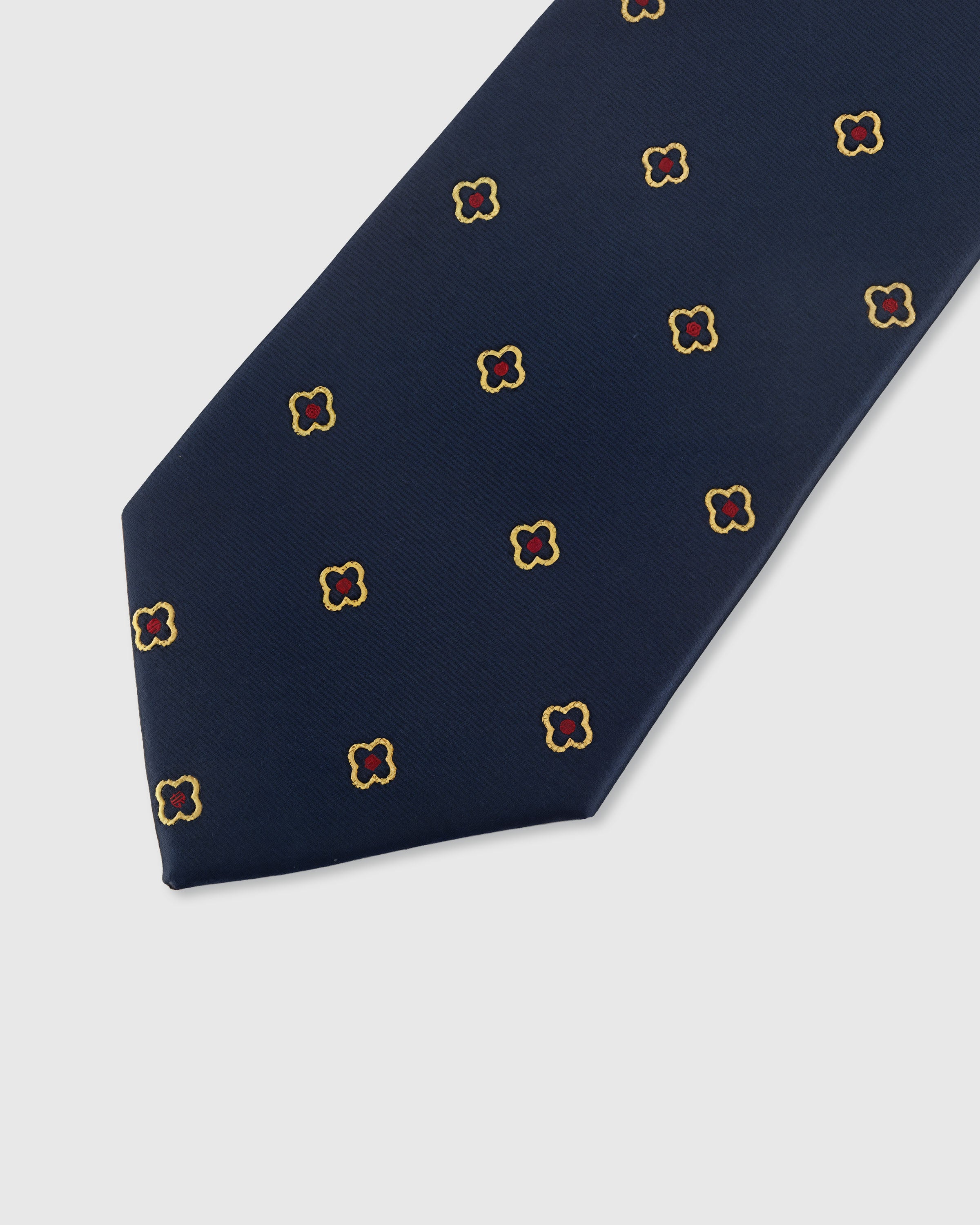 STICKYZOO NAVY QUATREFOIL TIE — hand-embroidered detail showing gold-outlined quatrefoil florets with crimson centers, stitched not printed