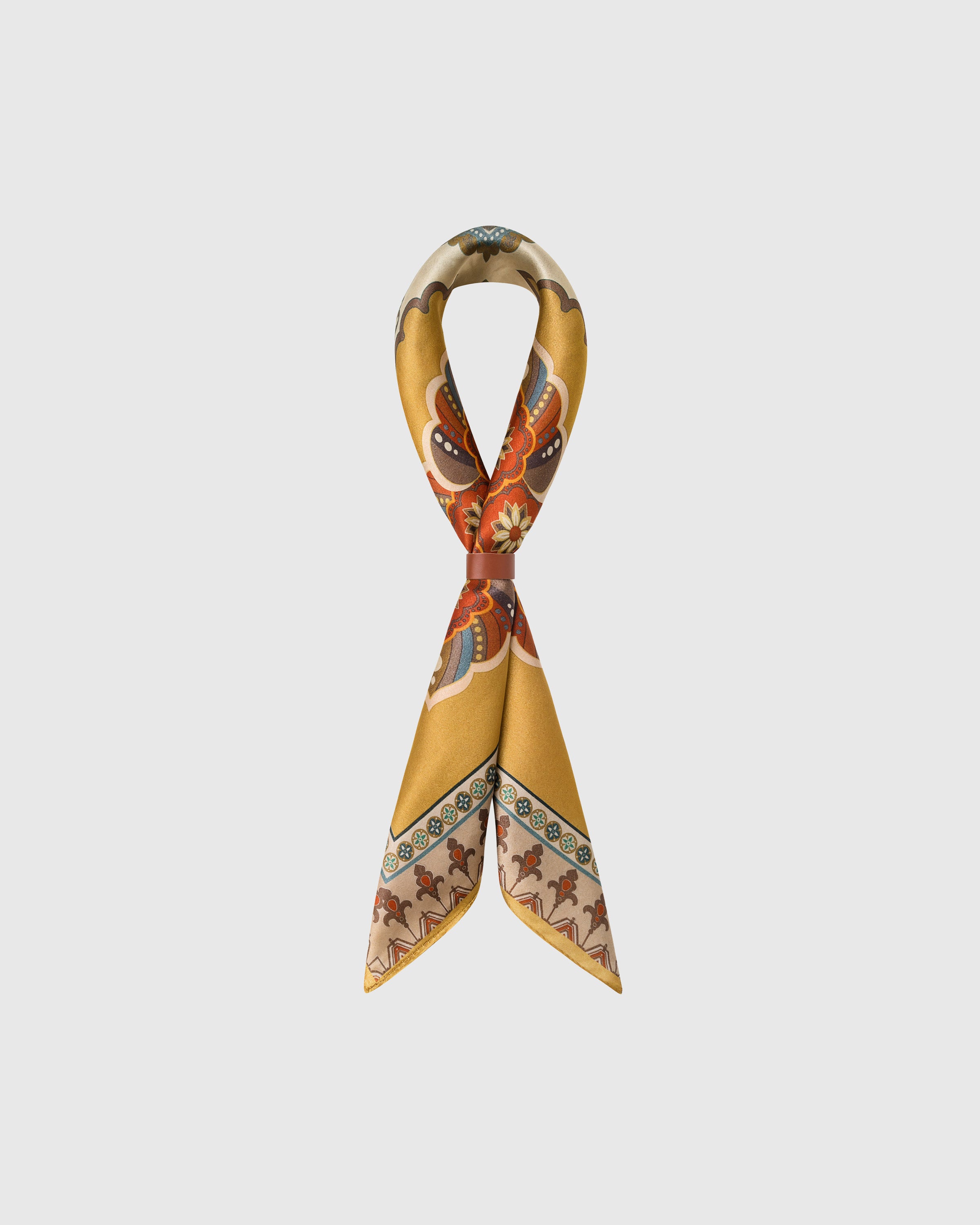 STICKYZOO saffron silk scarf looped through a leather slide showing the medallion print and warm border