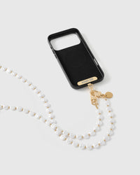 Black phone case fitted with the STICKYZOO gold Phone Strap Card and dual clasp, white faux-pearl strand looping down for hands-free carry.
