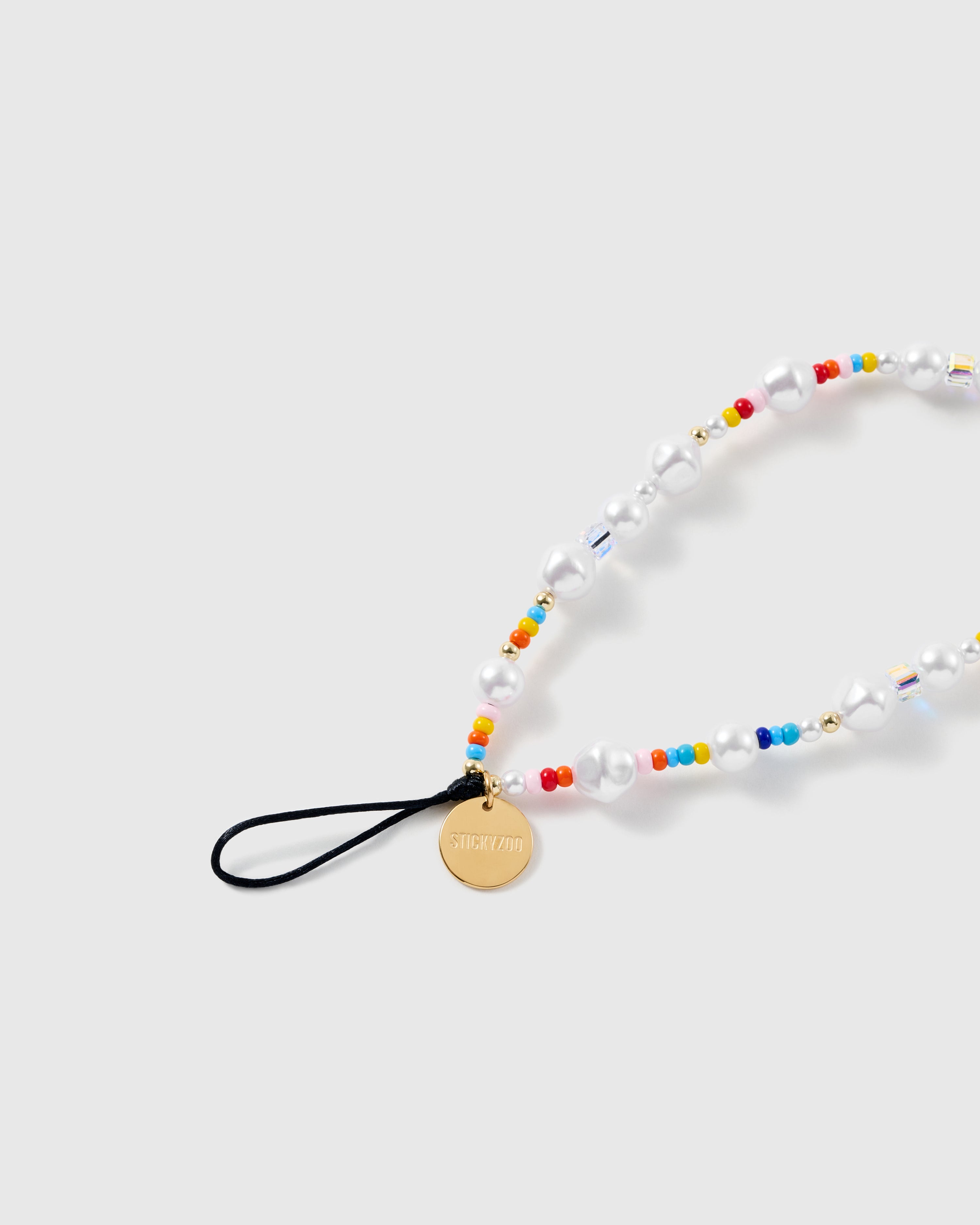 Close-up of the black stretch-cord loop and gold STICKYZOO disc, with baroque faux-pearls, rainbow seed beads and faceted clear beads.