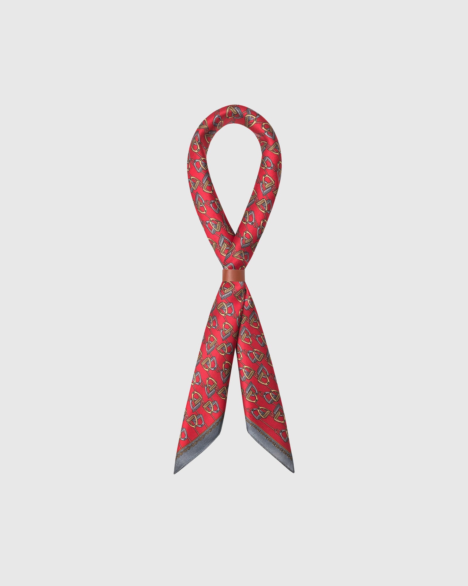 STICKYZOO equestrian silk scarf looped through a leather slide showing the stirrup print