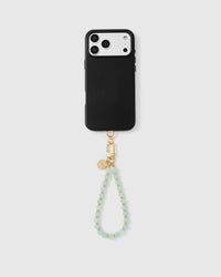 Full phone with mint green stone strap attached on grey background