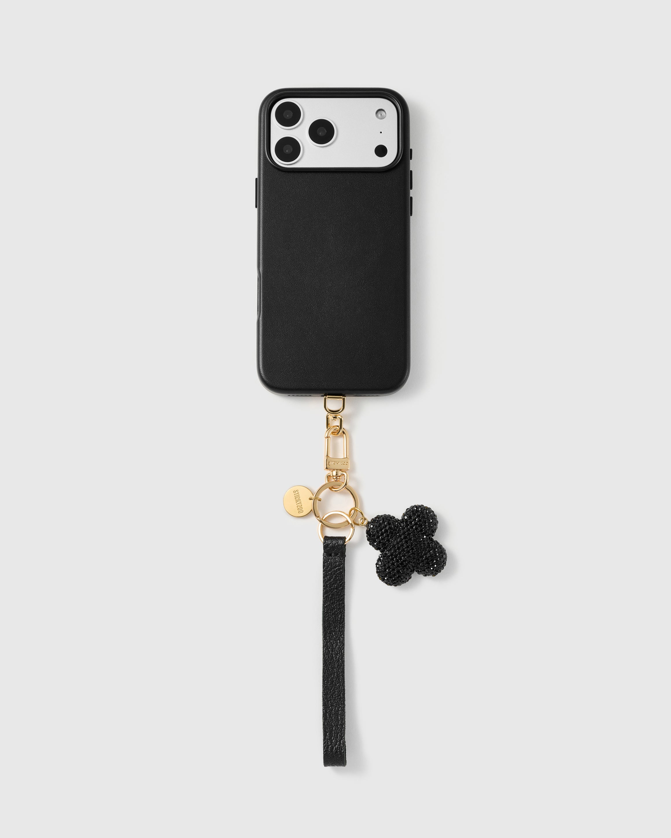 Close-up of four-leaf clover charm showing hand-set black crystal pavé on gold backing