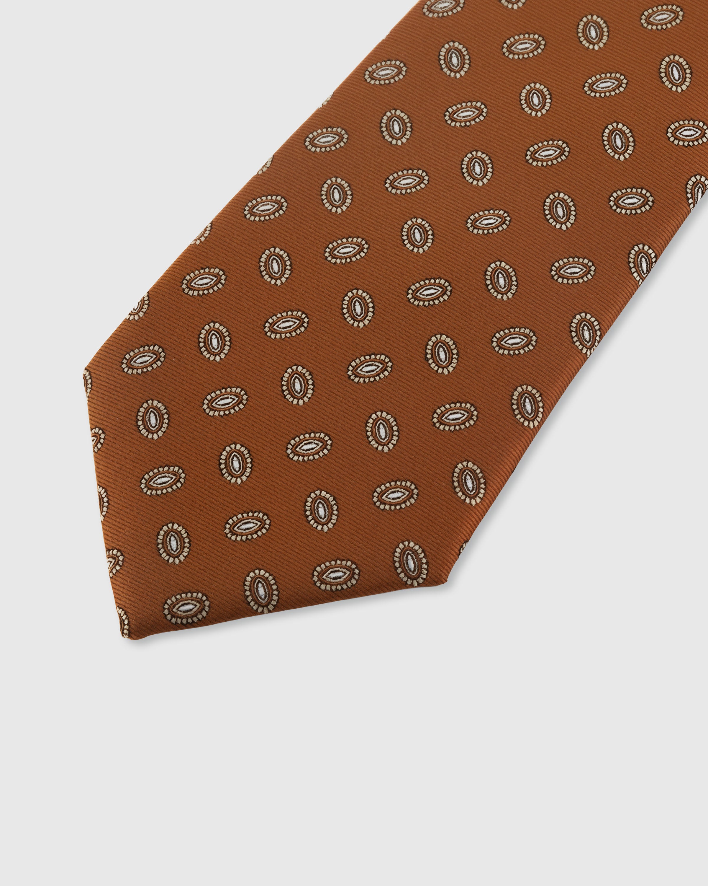 STICKYZOO COGNAC CAMEO TIE — hand-embroidered detail showing repeating oval cameo medallions in cream, stitched not printed
