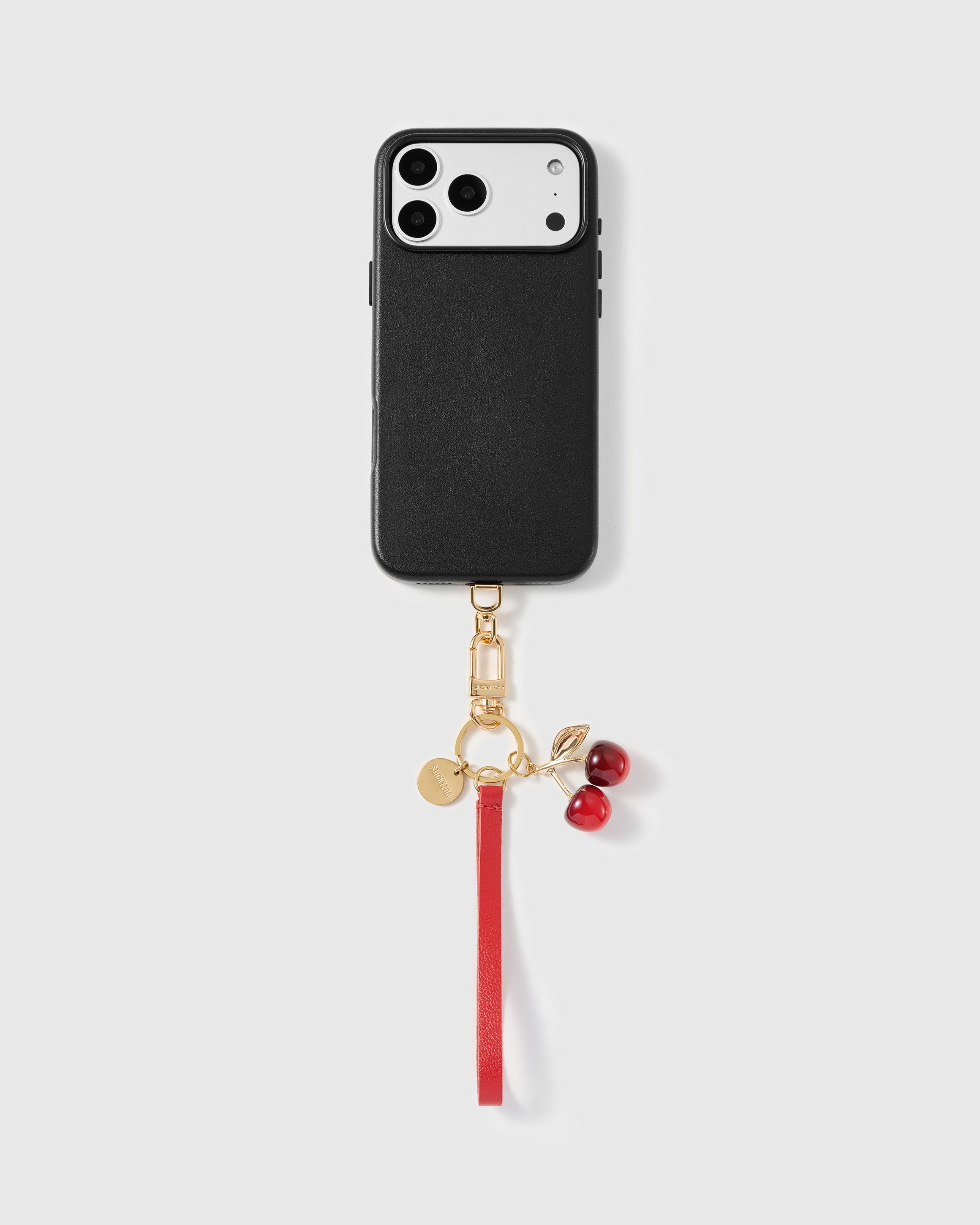 Close-up of glossy dark red cherry pair charm on gold-plated stem and leaf
