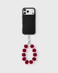 Crimson plush sphere phone strap attached to black phone case showing universal fit