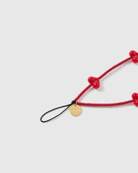 Close-up of glossy red puff-heart beads and the engraved STICKYZOO disc on a handmade phone strap