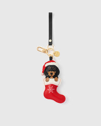 Handmade Santa Dachshund Stocking leather bag charm — full-grain French Alran goatskin, hand-stitched red stocking with embroidered snowflakes. STICKYZOO holiday collectible.