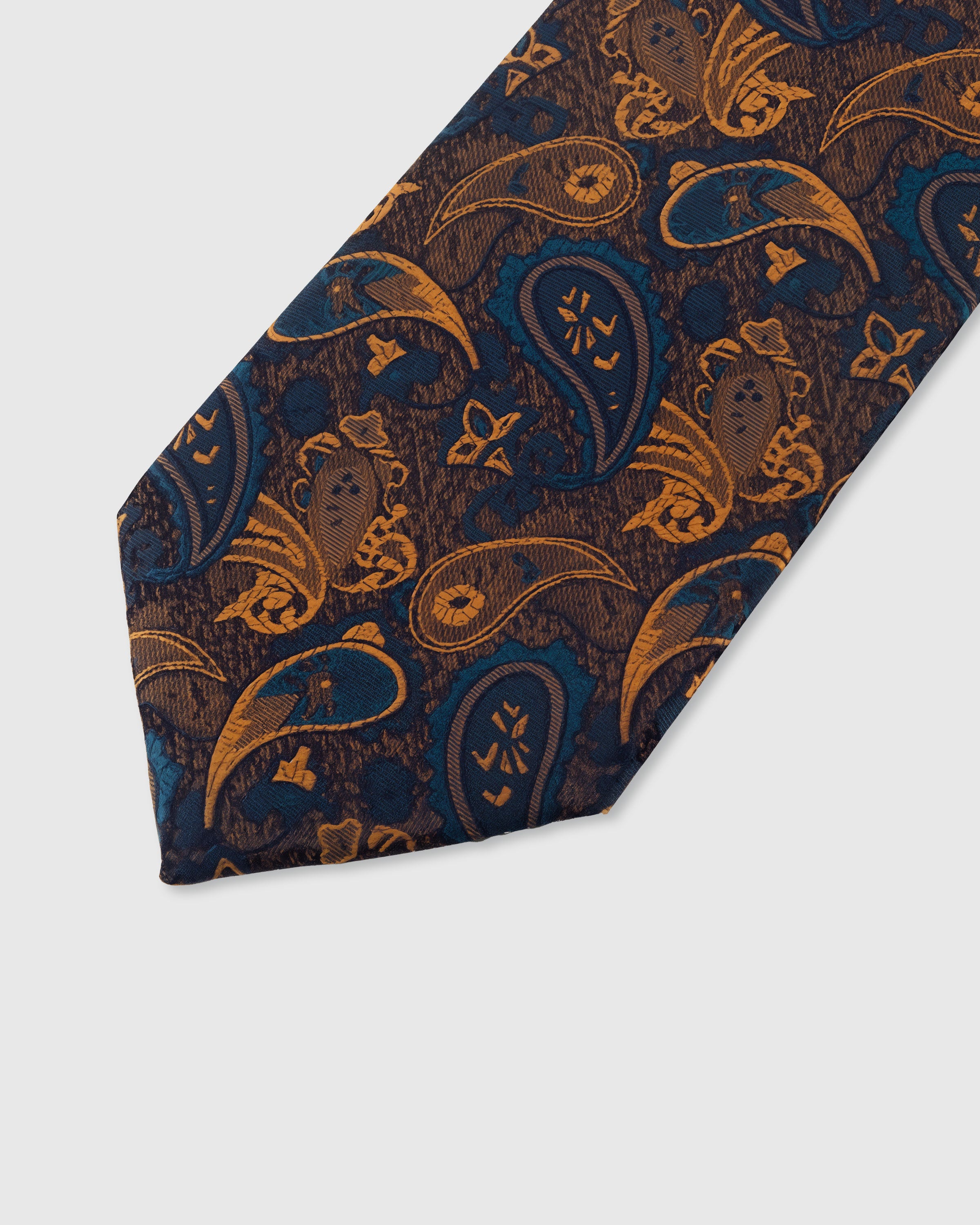 STICKYZOO INDIGO PAISLEY TIE — hand-embroidered detail showing golden-amber paisley teardrop motifs with floral detail, stitched not printed