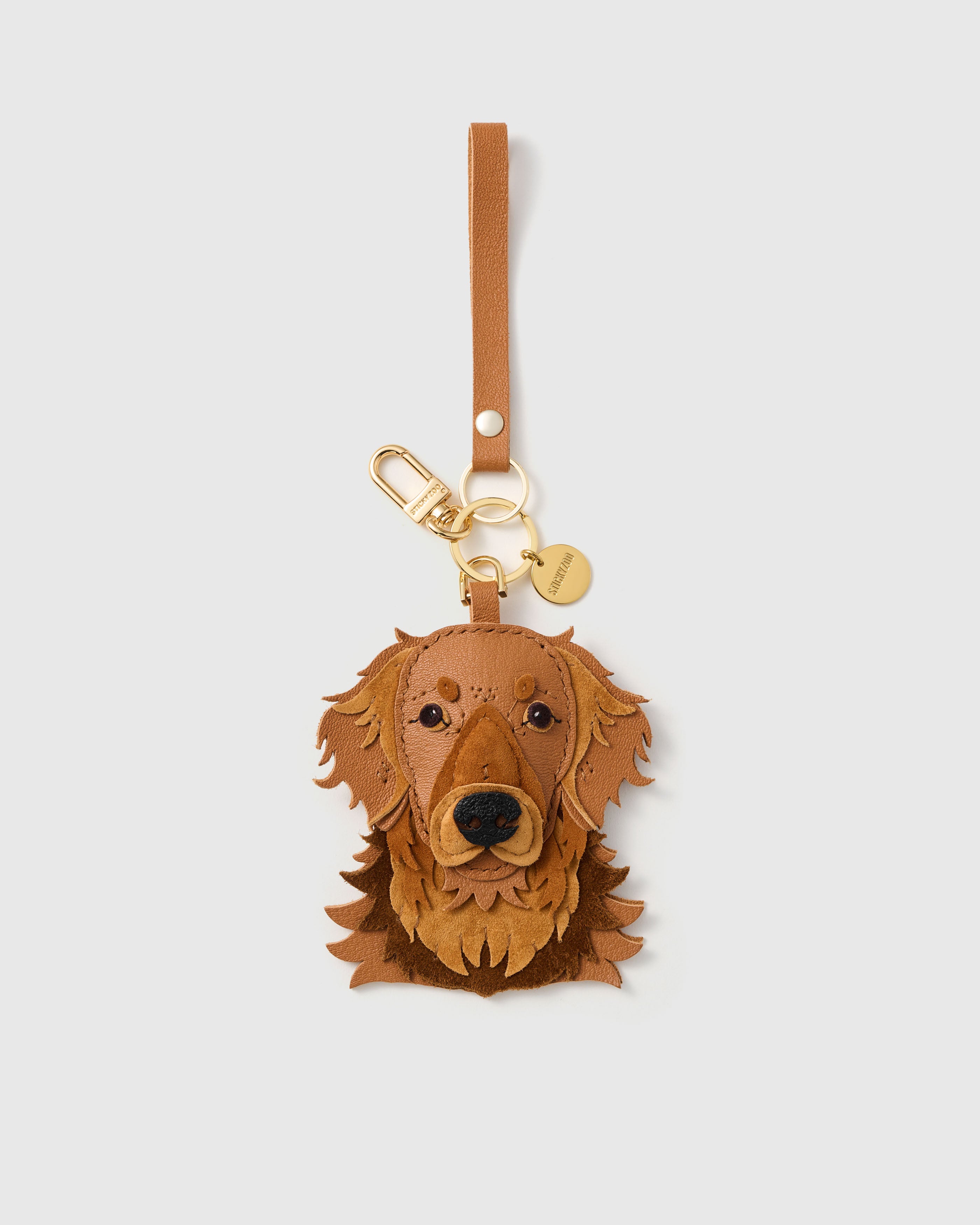 {{Keychain edition.}} 18K gold-plated clip with engraved STICKYZOO disc. Toffee and caramel French Alran goatskin + alcantara suede.
