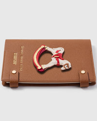 Rocking horse charm detail showing hand-layered white, red, and gold leather with saddle and rockers on STICKYZOO A5 notebook