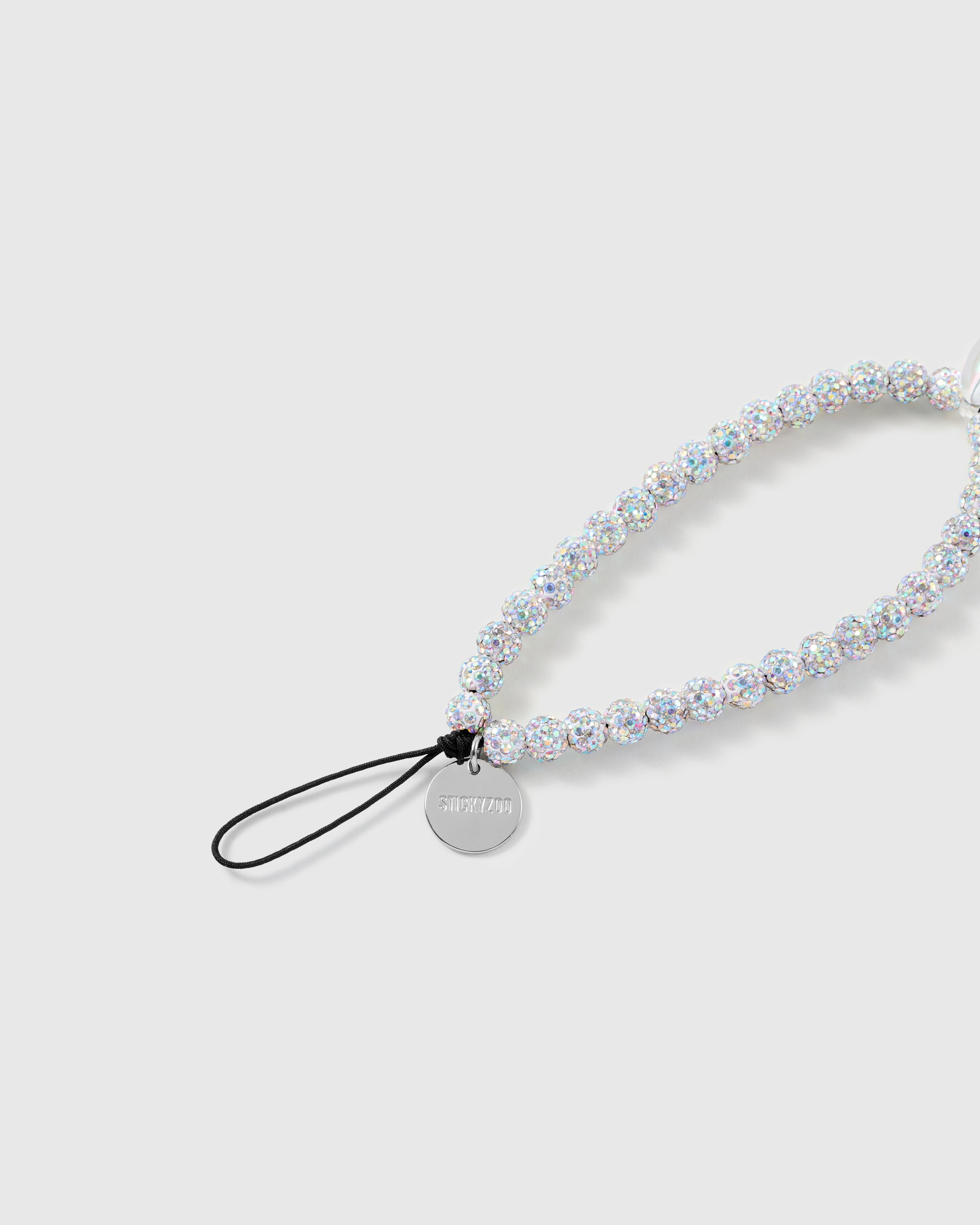 Close-up of the black stretch-cord loop and engraved silver STICKYZOO disc, with iridescent glitter beads catching the light.