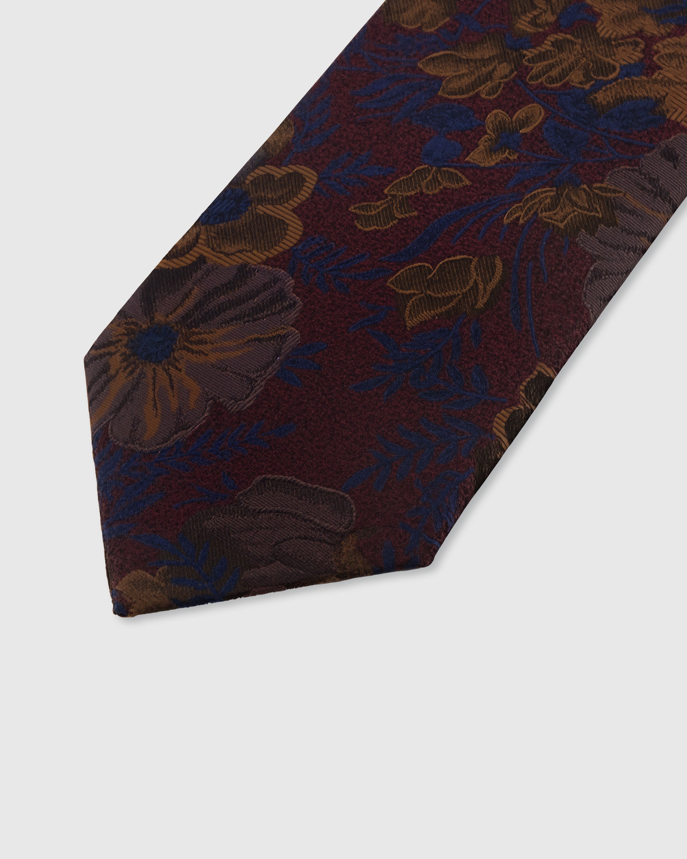 STICKYZOO BORDEAUX BLOSSOM TIE — hand-embroidered detail showing bronze and navy botanical blooms with blue fronds, stitched not printed