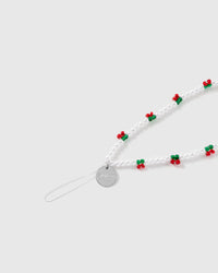 Close-up of the white stretch-cord loop and engraved silver-tone STICKYZOO disc, with faux-pearl beads and a red-and-green berry cluster.