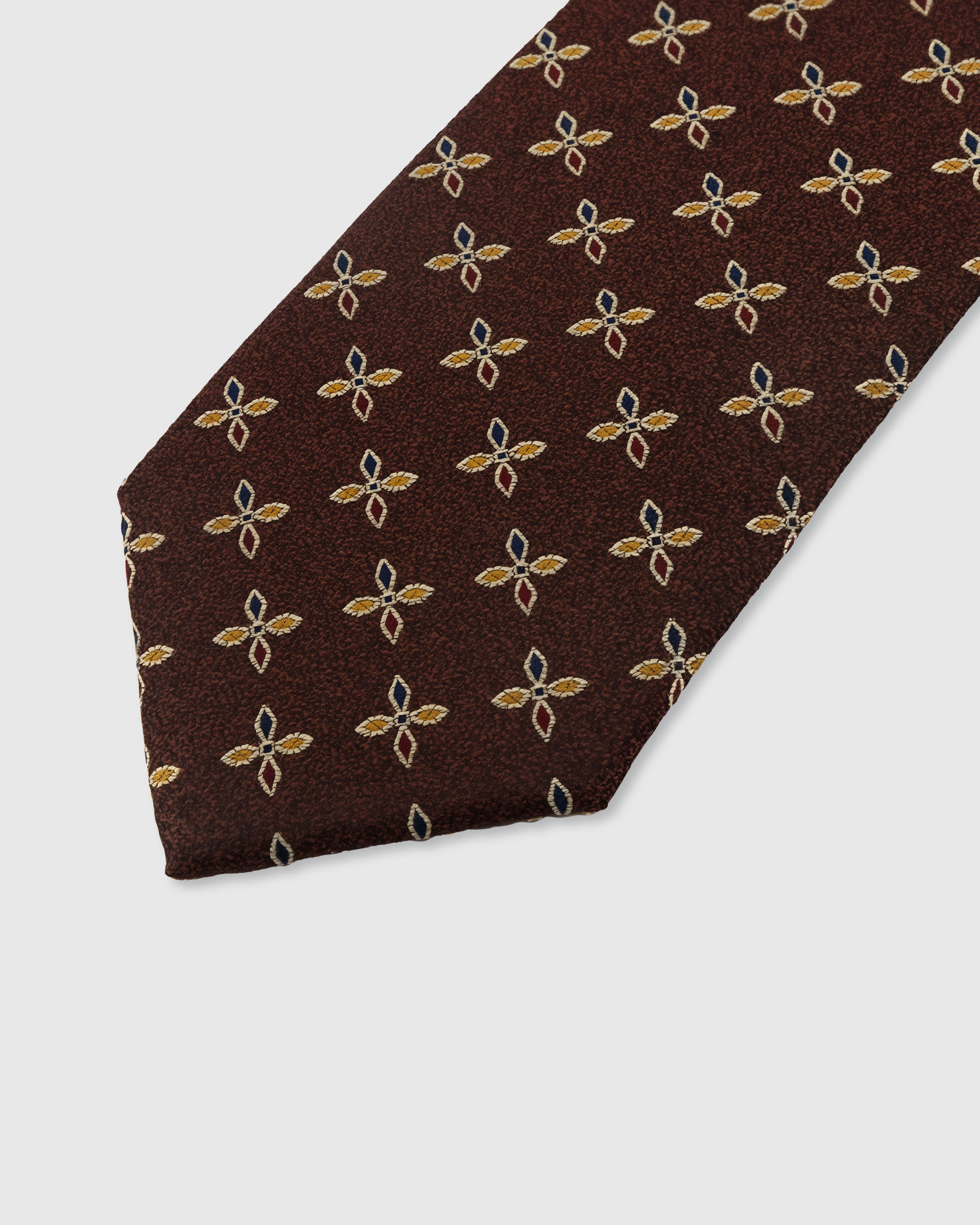 STICKYZOO MAHOGANY PETAL TIE — hand-embroidered detail showing gold and teal four-petal leaf motifs, stitched not printed