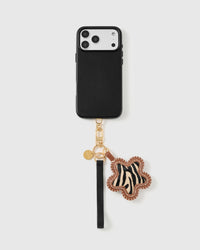 Zebra flower leather phone strap clipped to a black phone case, worn hands-free from the wrist