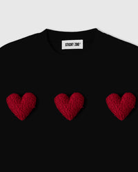 Close-up of burgundy plush hearts on black cotton showing textured sherpa surface