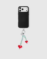 Full phone with dual jade heart strap hanging from case on grey background
