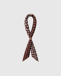STICKYZOO oxblood patchwork silk scarf twisted through a leather ring showing the four-quadrant print