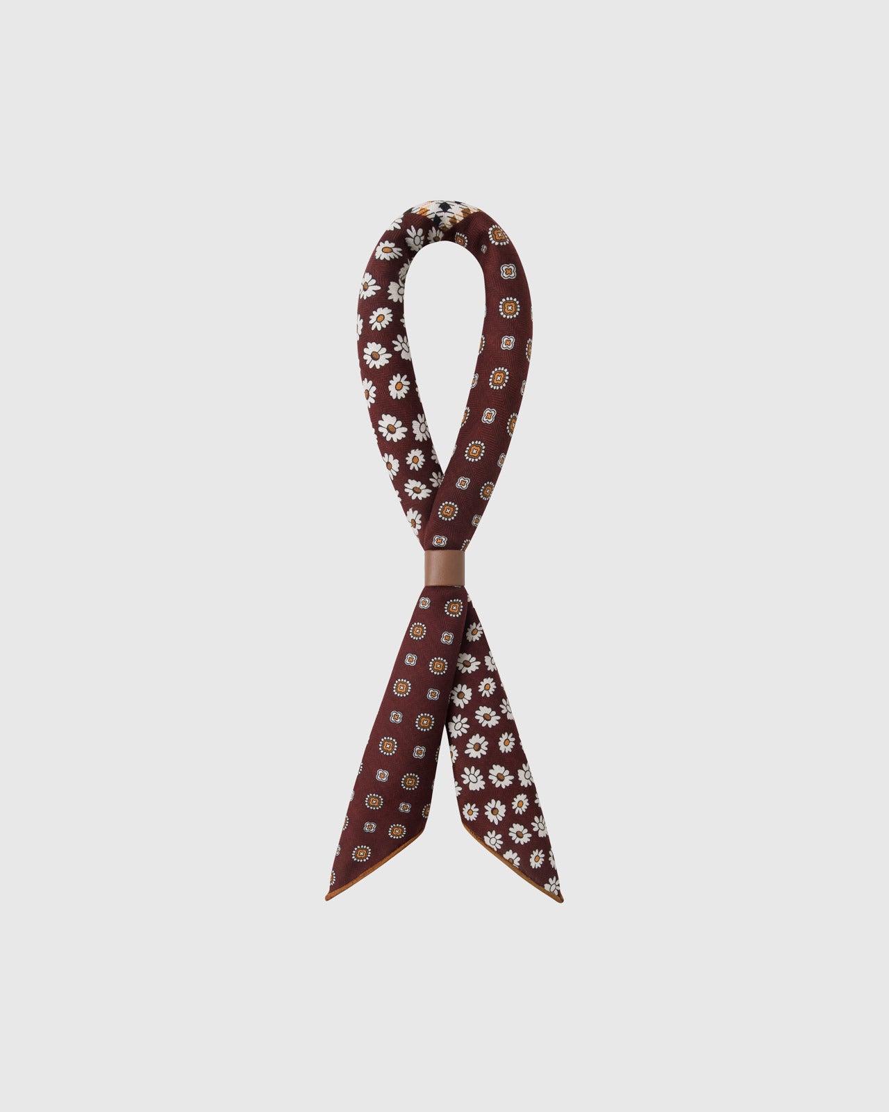 STICKYZOO oxblood patchwork silk scarf twisted through a leather ring showing the four-quadrant print