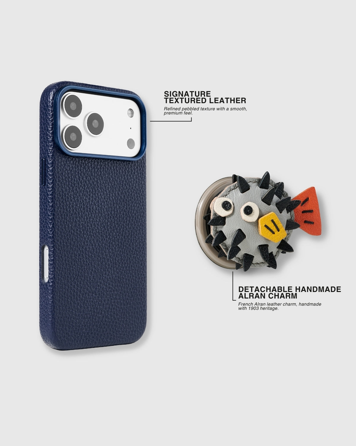 {{Detachable charm system.}} Navy leather case with pufferfish charm separated — showing magnetic attachment base, pebbled texture, and handmade French Alran leather construction with 3D layered spikes.