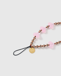 Close-up of the black stretch-cord loop and engraved gold STICKYZOO disc, with striped barrel beads, rust-brown rounds and a pink jelly heart