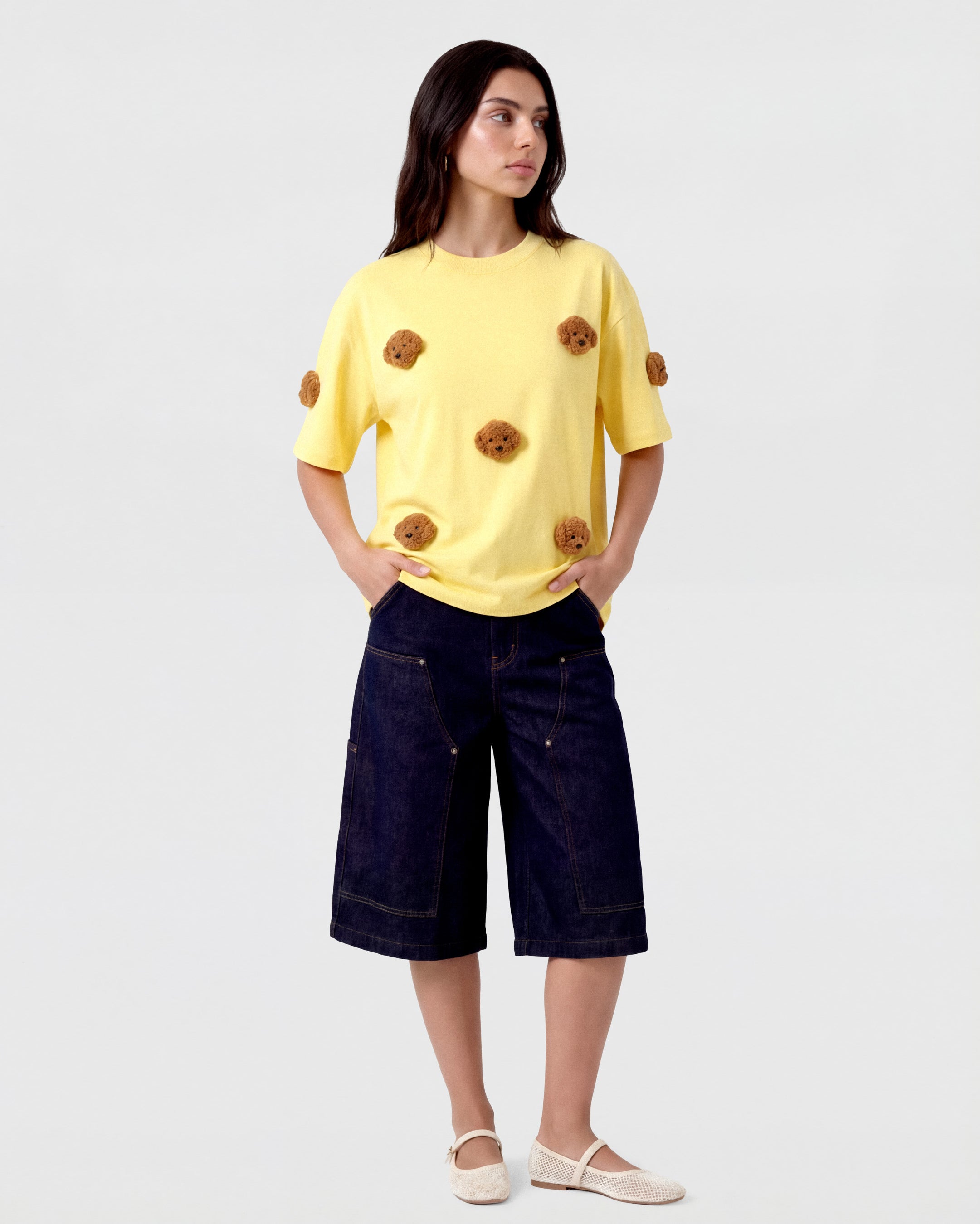 {{Not printed — stitched}} Model styling lemon Poodle Parade T-Shirt with hands in pockets showing relaxed silhouette