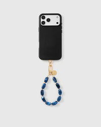 Full phone with indigo marble stone strap attached on grey background