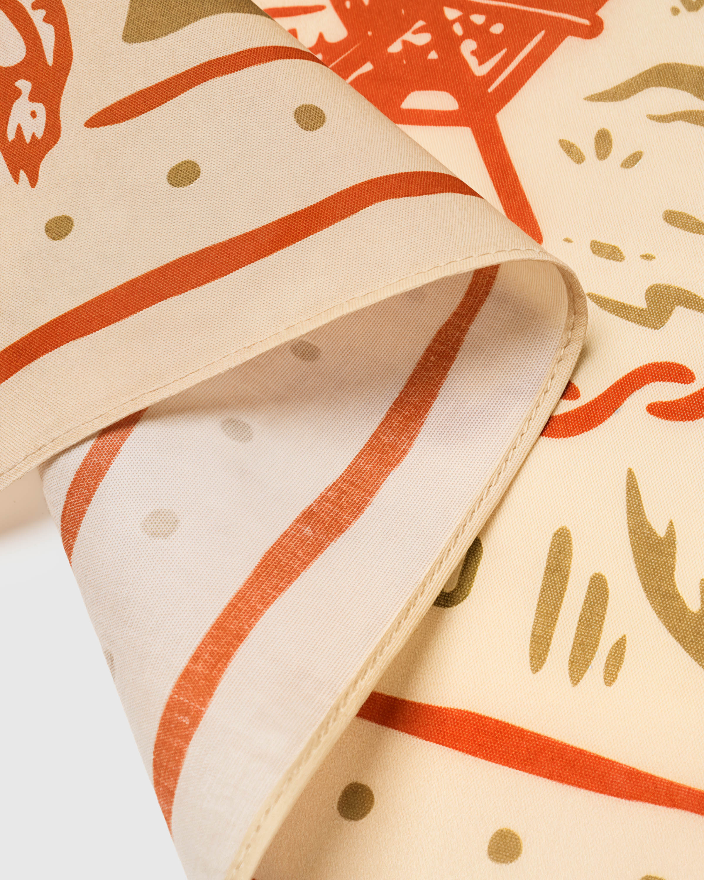 Edge of the desert lounge silk scarf showing the rust border and cream field on pure silk