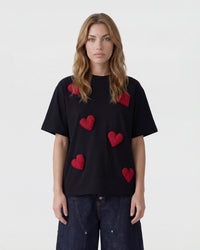 Close-up of hand-stitched plush heart applique showing textured burgundy plush surface on black cotton