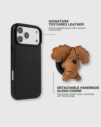 Poodle puppy charm detached from textured black leather phone case showing magnetic grip connection. French Alran leather charm hand-cut with curly ear detail and layered paws. 5,000+ Reviews.