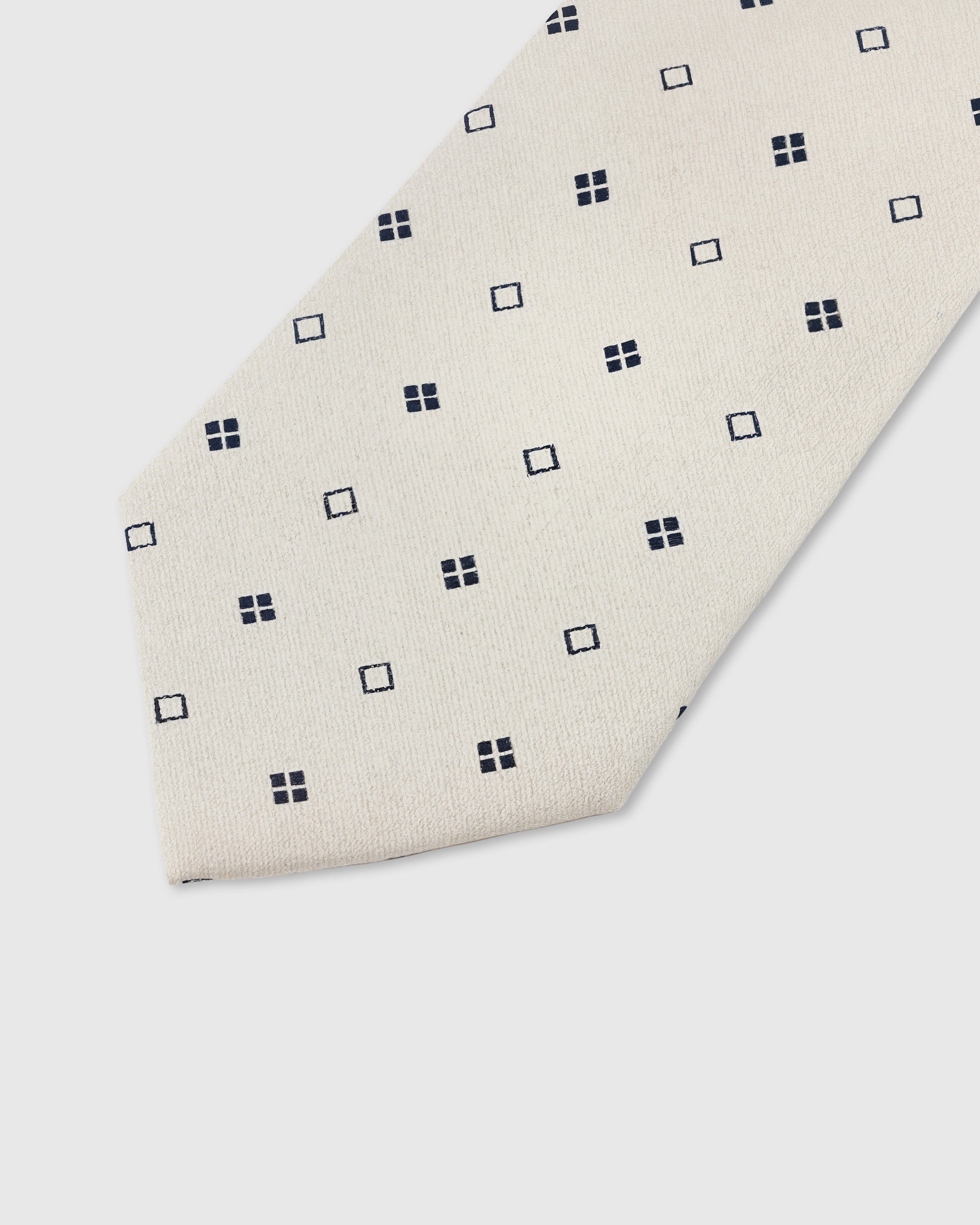 Navy square dot detail on pearl mulberry silk tie showing raised hand-embroidered geometric motifs by STICKYZOO