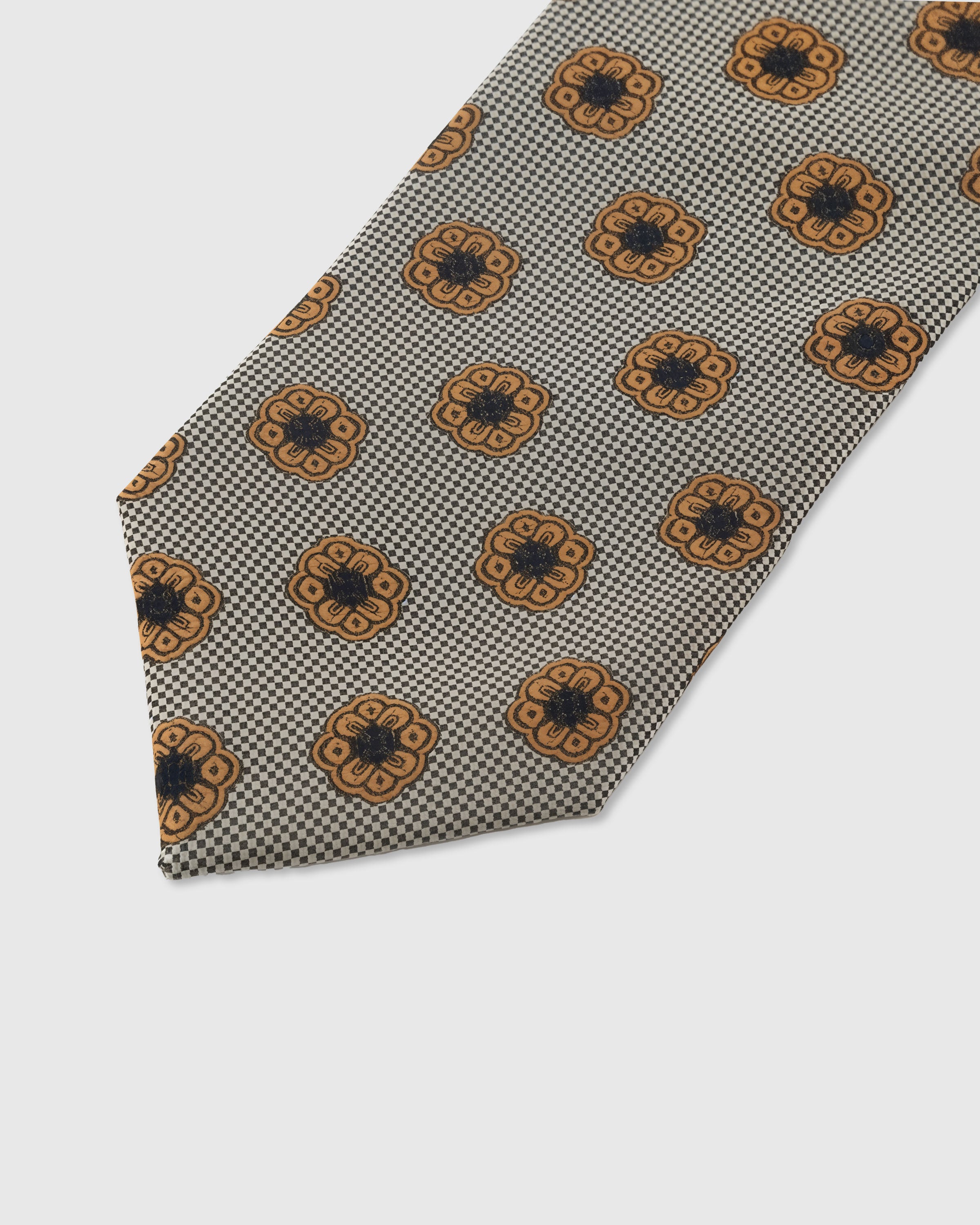 Amber rosette medallion detail on pewter houndstooth mulberry silk tie showing raised hand-embroidered thread by STICKYZOO