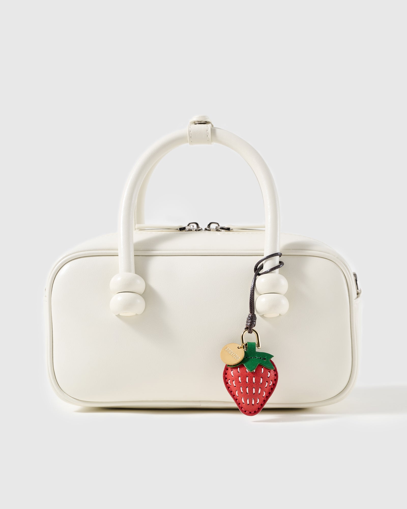 STICKYZOO leather strawberry charm shown on a white handbag, French goatskin, gift-ready and handmade