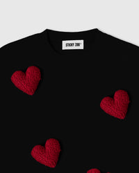 Detail view of multiple plush hearts on black cotton showing dimensional depth and scattered placement