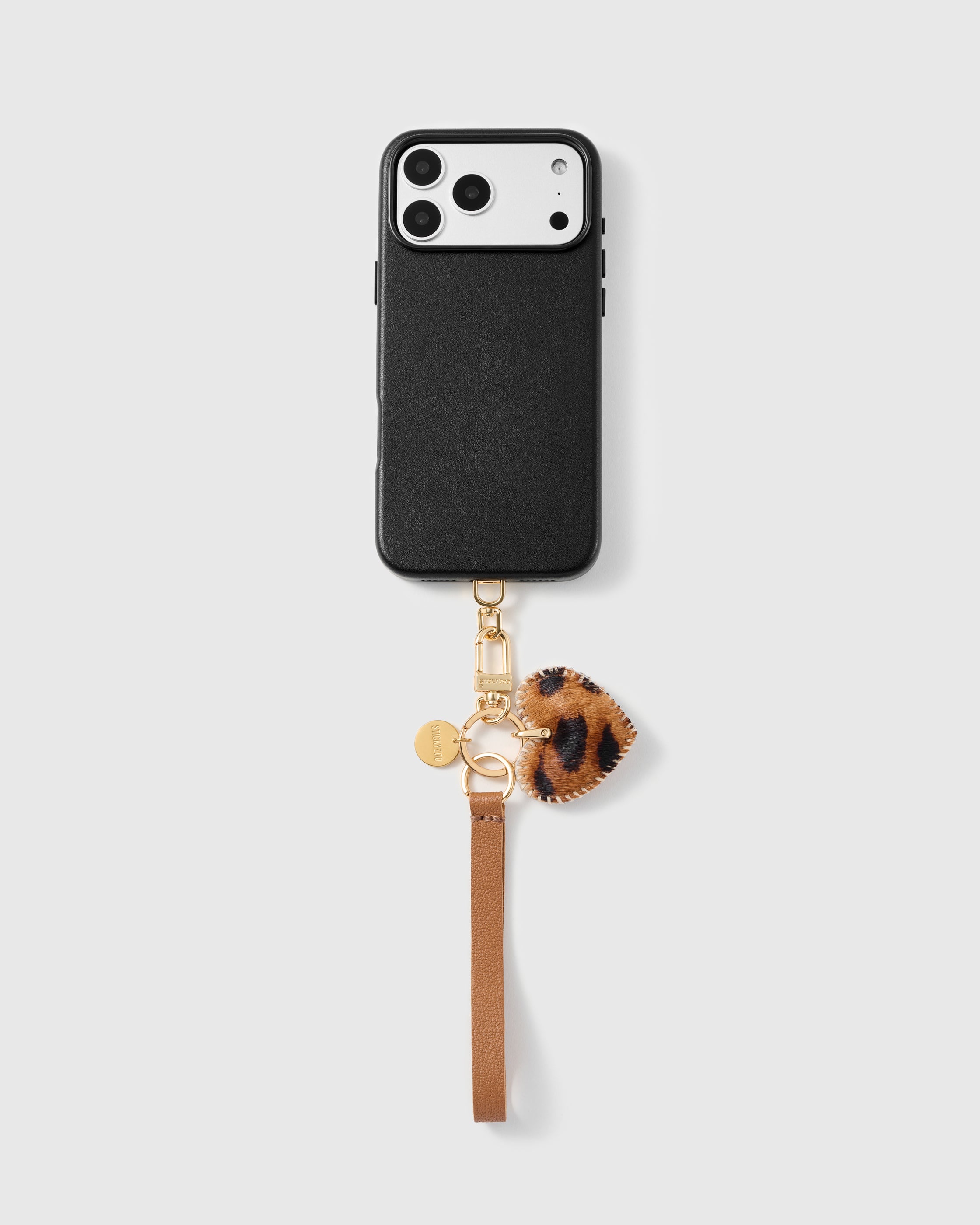 Leopard heart leather phone strap clipped to a black phone case, hands-free cognac wrist strap