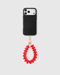 Full phone with crimson heart bead strap attached on light grey background