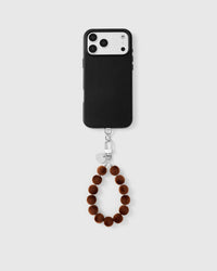 Full phone with toffee pom strap attached on light grey background