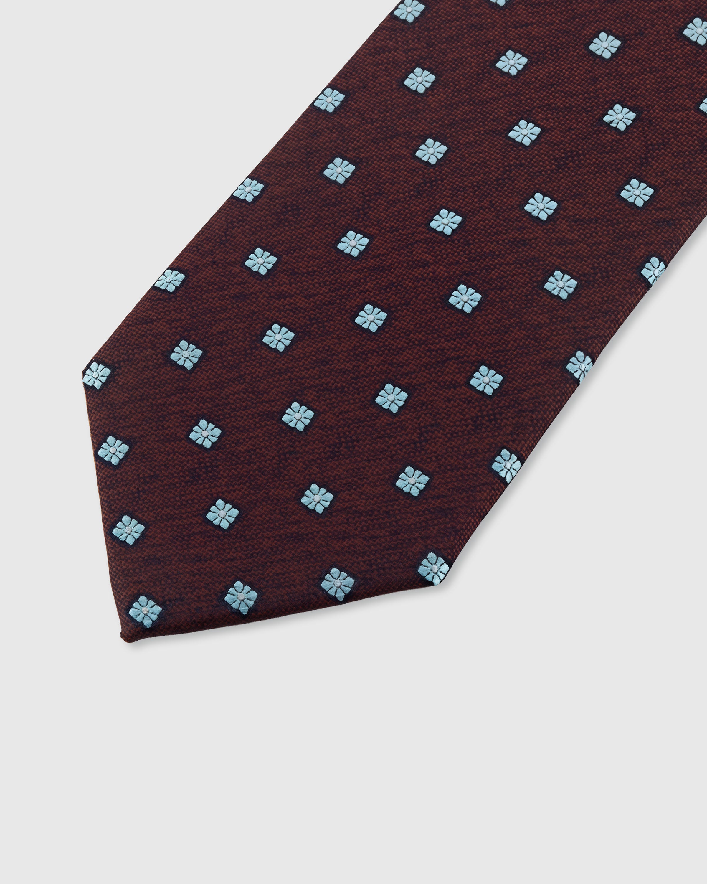 STICKYZOO CLARET FLORET TIE — hand-embroidered detail showing pale blue four-petal floret motifs, stitched not printed