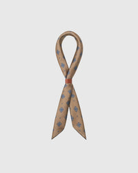 Camel silk foulard scarf draped in a ribbon fold with a slim leather slide showing the diamond medallion print