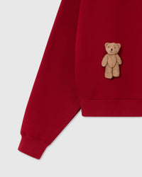 Detail of ribbed hem and cuff construction on red Saint Teddy Bear Sweatshirt