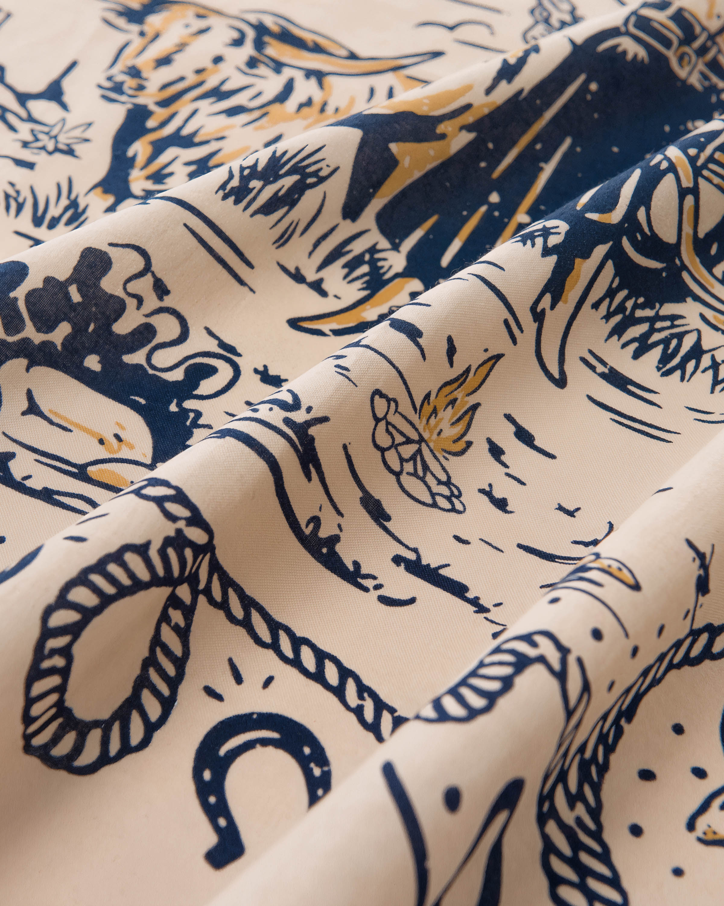 Detail of the hand-illustrated cowgirl scene printed in navy and butter yellow on the cream silk field
```