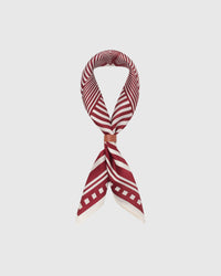Silk op-art scarf coiled into a soft loop with a leather wrap showing the small-square drape and graphic field