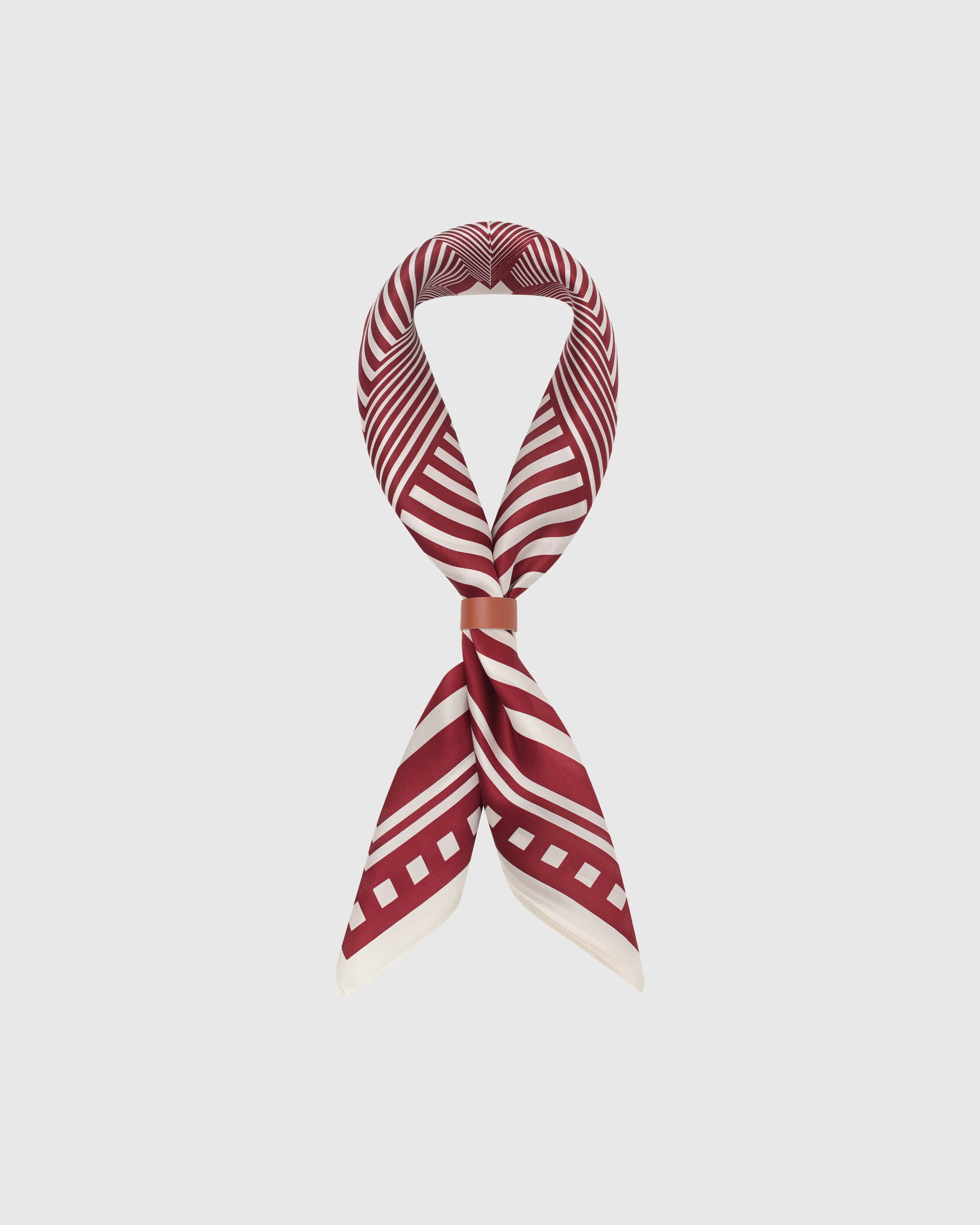 Silk op-art scarf coiled into a soft loop with a leather wrap showing the small-square drape and graphic field