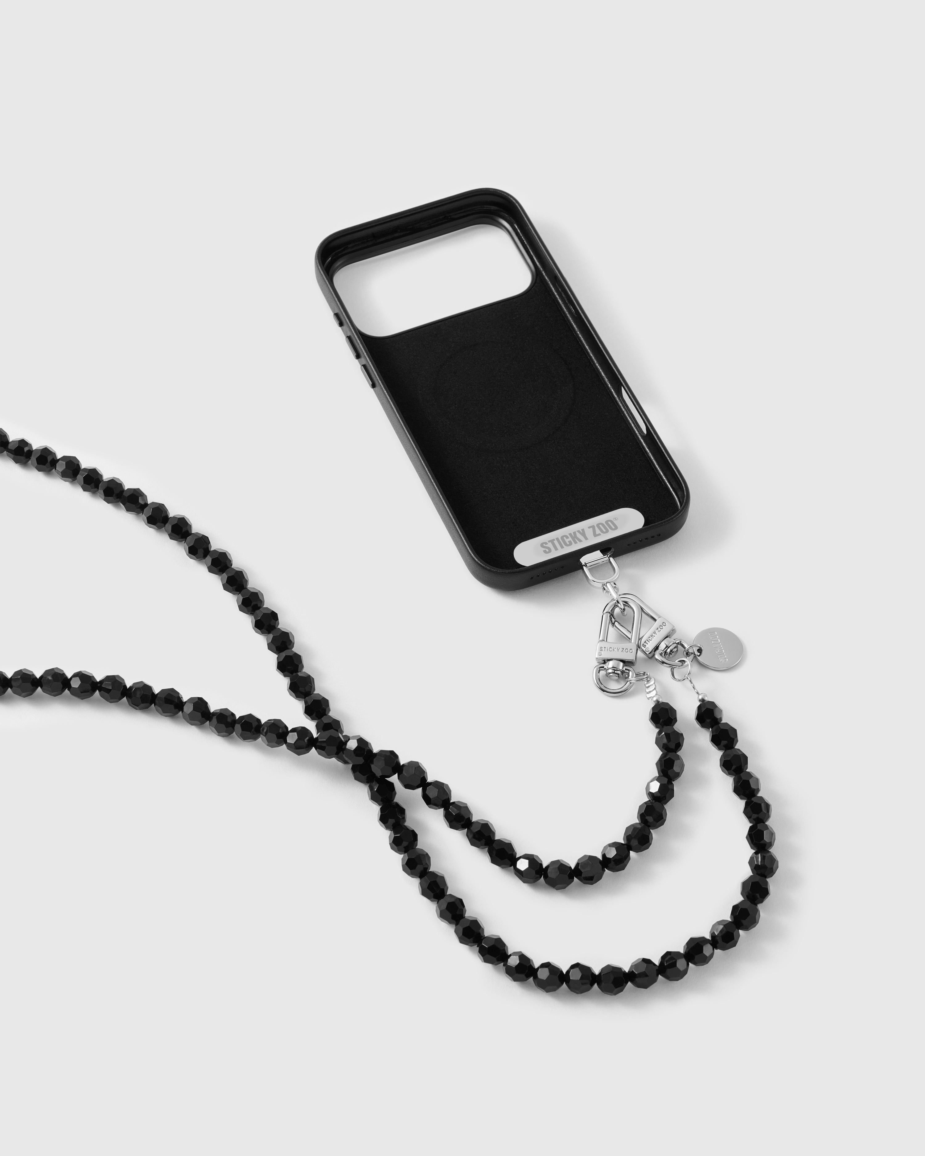 Black phone case engraved STICKYZOO with a silver-tone dual clasp and a looping strand of faceted jet-black beads.